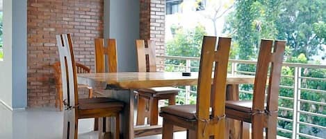 A dining area with a brick wall, wooden chairs, and a table.