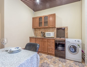 Compact kitchen with appliances, dining table, and tile flooring.