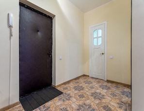 Enter a room with a dark brown door and a white door featuring a small window, set against a backdrop of patterned tiles.