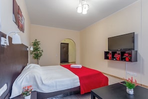 Relax in a stylishly designed room with a comfortable bed, flat-screen TV, and a potted plant.