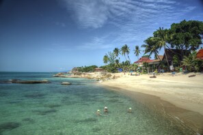 A beach with clear turquoise water, palm trees, and a sandy shore.