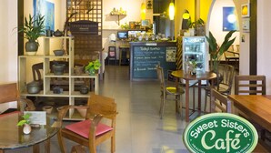 Un interior de café con muebles de madera, una pizarra de menú y varias plantas.