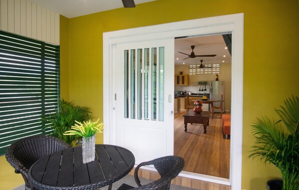 A room with a dining table and chairs, a white door with glass panels, and a view into a kitchen area.