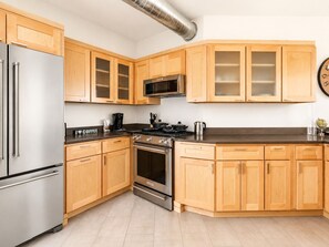 Une cuisine moderne avec des meubles en bois, des appareils en acier inoxydable et un four à micro-ondes.