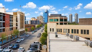 A cityscape with a clear sky, a mix of modern and older buildings, and a street lined with parked cars. - Upscale 3BR Penthouse by CozySuites (Indianapolis)