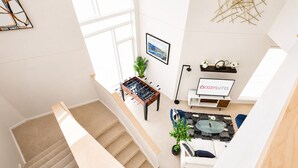 A modern living room with a sofa, coffee table, and a foosball table. - Upscale 3BR Penthouse by CozySuites (Indianapolis)