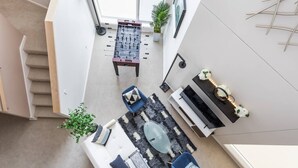 A modern living room with a foosball table, a sofa, a coffee table, and a small side table with decorative items. - Upscale 3BR Penthouse by CozySuites (Indianapolis)