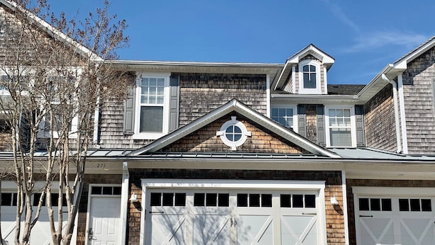 A two-story house with a garage, a small attic window, and a chimney.