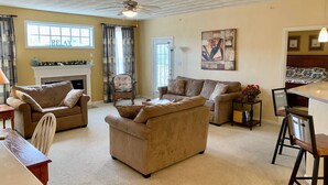 A living room with a fireplace, two sofas, a dining table, and a ceiling fan.