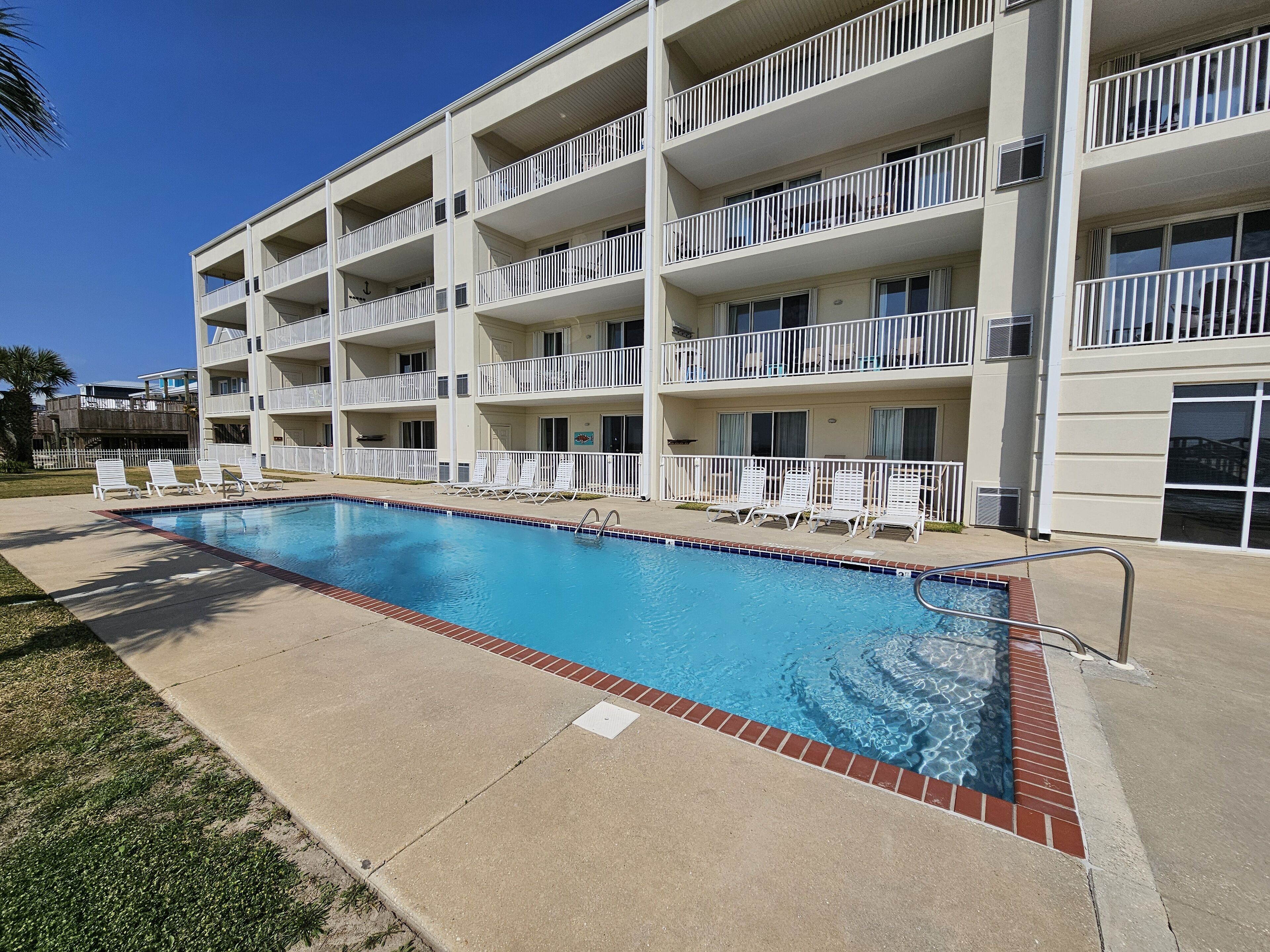 A multi-story hotel with a swimming pool, outdoor seating, and balconies.