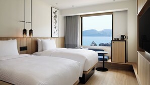 A modern hotel room with two beds, a large window with a view of the sea, a small table, and a television. - Fairfield by Marriott Wakayama Kushimoto (Kushimoto)