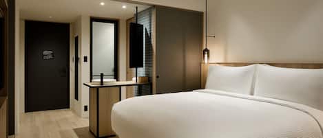 Ein modernes Hotelzimmer mit einem großen Bett, einem Nachttisch, einem Spiegel und einer Wandleuchte.