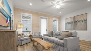 Un salon moderne avec un canapé gris, une table basse en bois et un ventilateur de plafond.