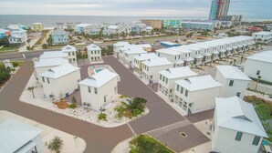 Une zone résidentielle côtière avec plusieurs maisons à deux étages, une route et une plage en arrière-plan.