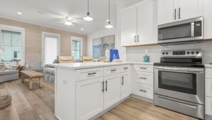Une cuisine moderne avec des meubles blancs, un four en acier inoxydable et un four à micro-ondes. On y trouve également un coin repas avec une table et des chaises.