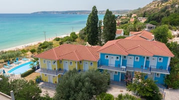 A coastal hotel with a swimming pool, two-story buildings, and a beach view.