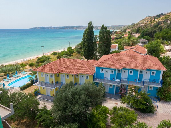 Un hotel frente al mar con piscina, edificios de dos pisos y vista a la playa.