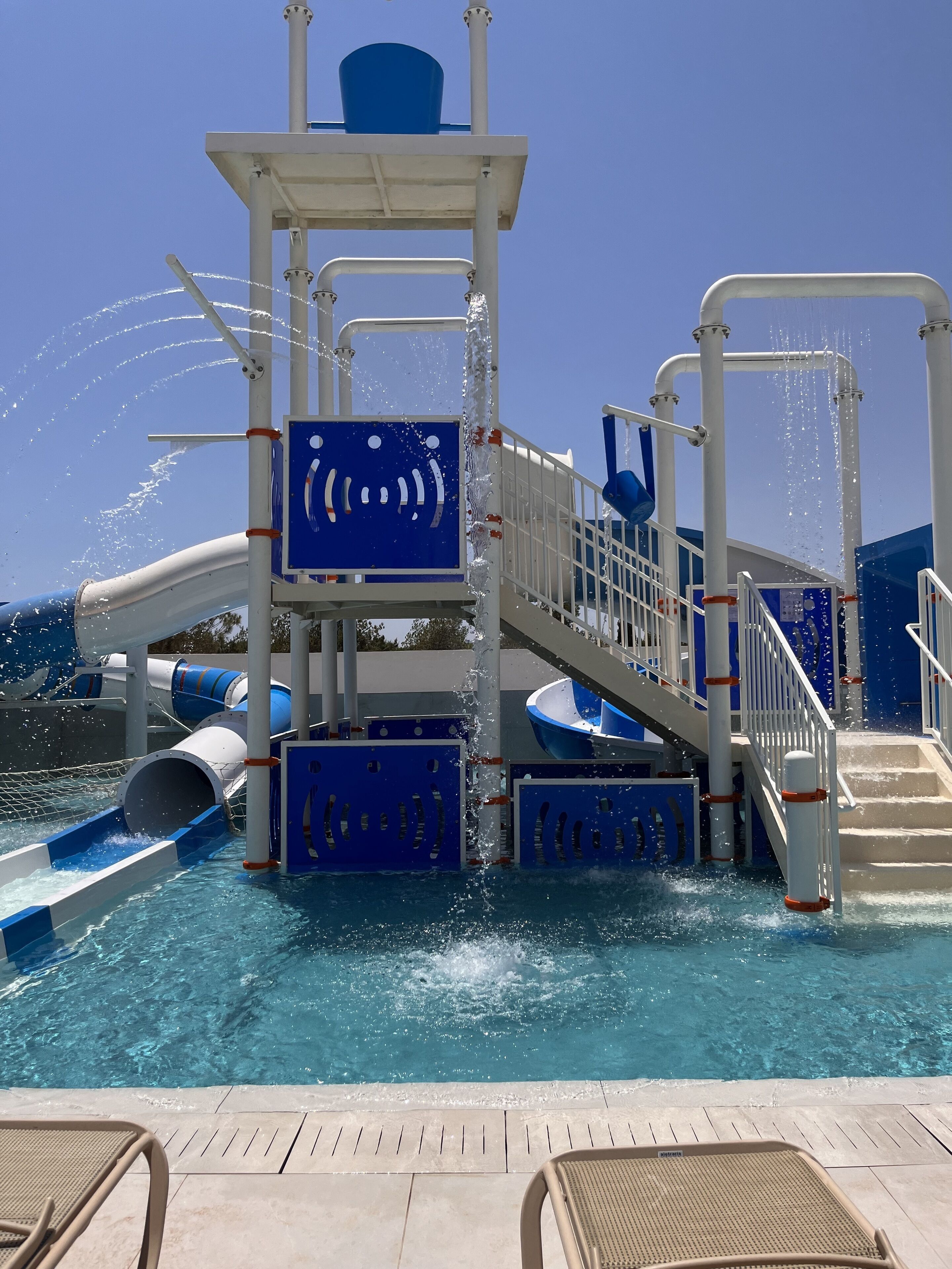 A water play area with slides and water jets on a pool deck.