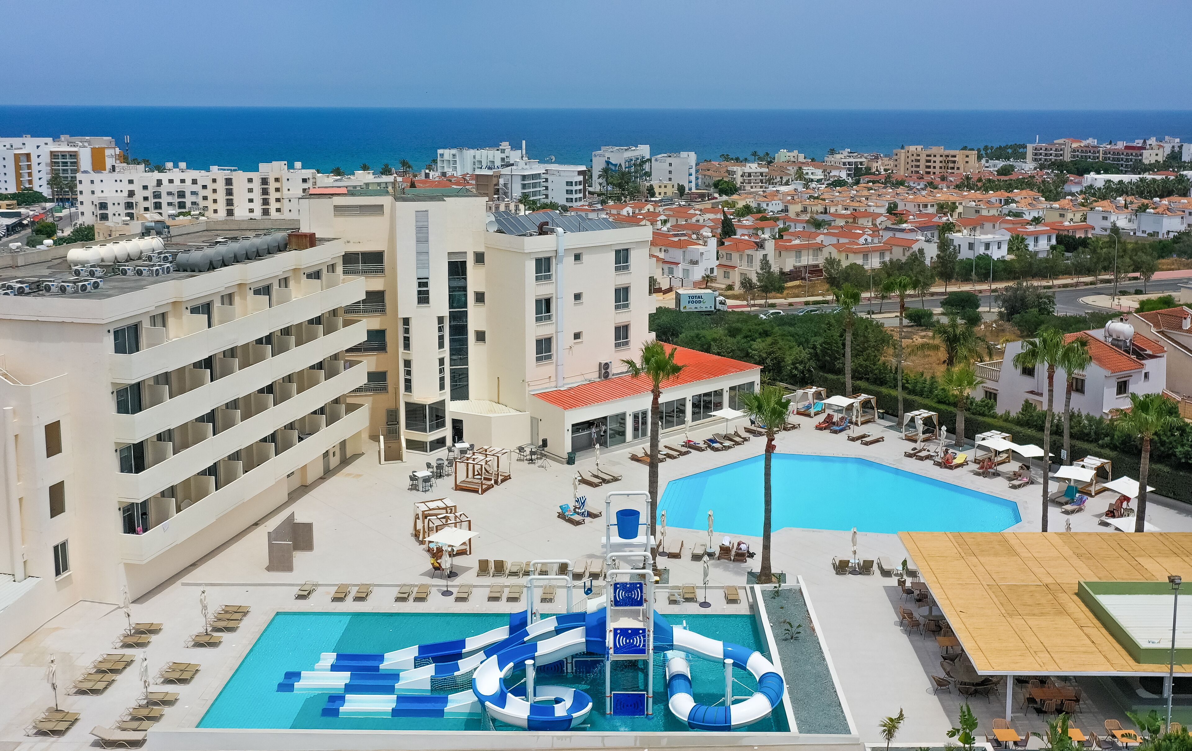A hotel with a pool area, including a water slide and lounge chairs.