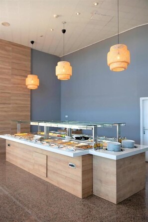 A buffet setup with multiple food stations, a wooden counter, and hanging pendant lights.