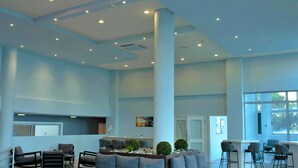 A spacious lobby with a central seating area, a reception desk, and large windows providing natural light. - Toxotis Hotel  (Paralimni)