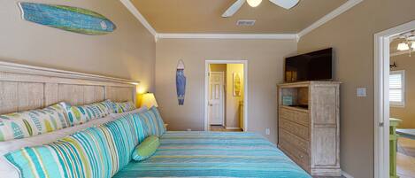 Un dormitorio con cama, ventilador de techo, decoración de tabla de surf, televisor y un mueble de madera.