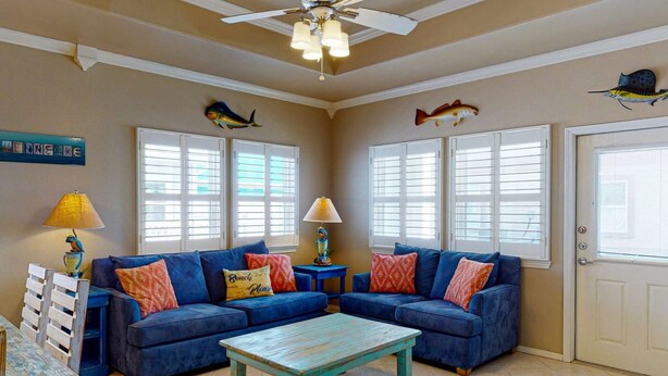 A living room with a blue sofa, a wooden coffee table, and decorative fish on the walls. - Shared Pool, Near Beach, Pet Friendly (Port Aransas)