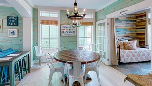 Un comedor con una mesa redonda y sillas, una araña y un letrero que dice "PEACHY PELICAN BEACH HOUSE PORT ARANSAS, TX".