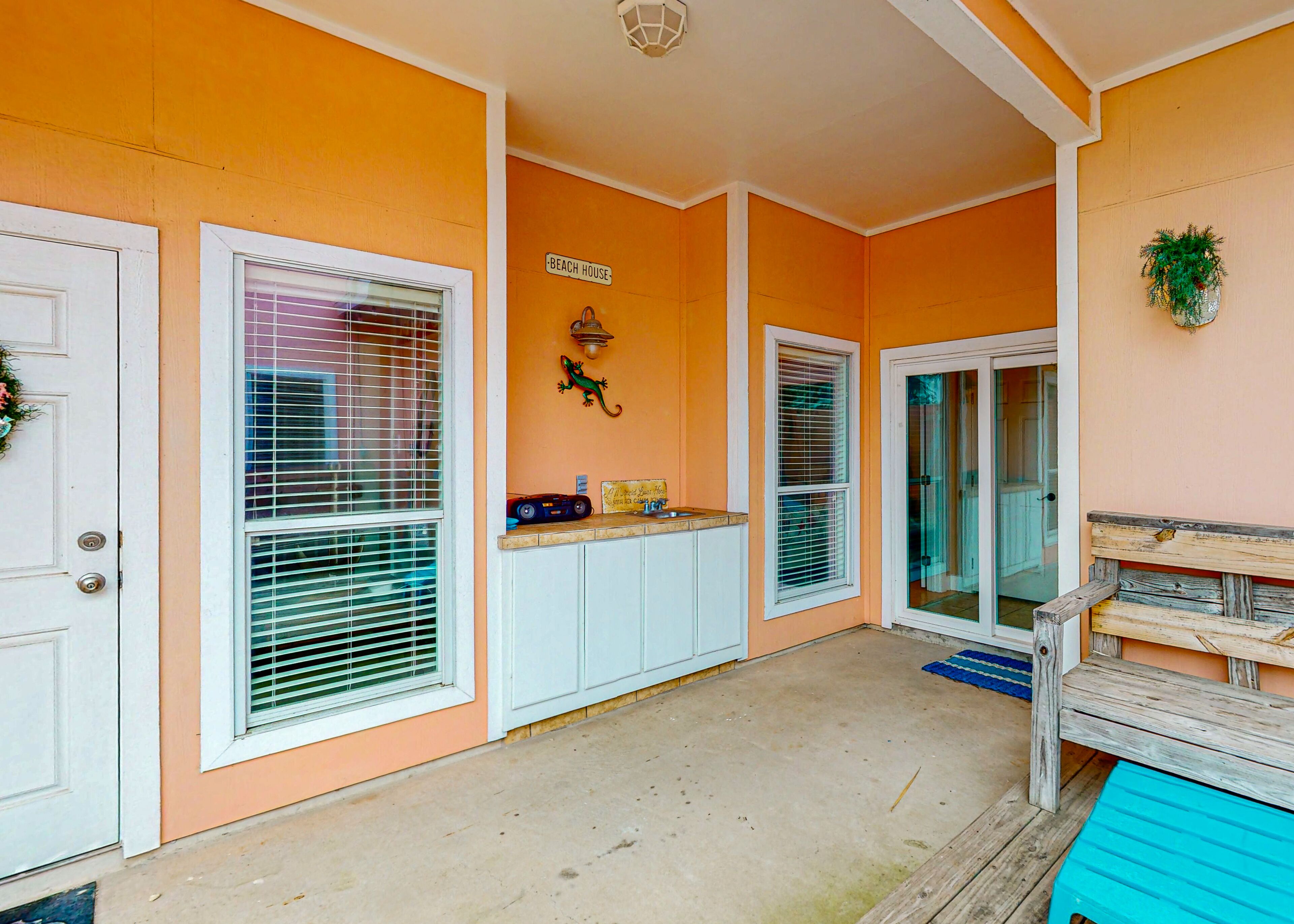 A beach-themed exterior with a sign reading "BEACH HOUSE," a small shelf with items, and a wooden bench.