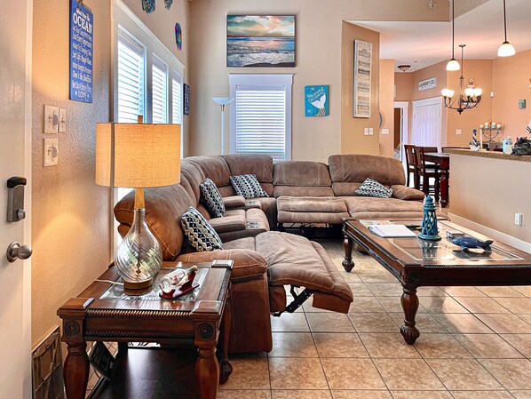 A living room with a sectional sofa, a coffee table, and a dining table.