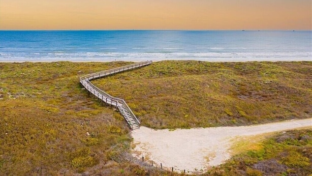 Ein Küstenpfad mit einem hölzernen Steg, der zum Strand führt.