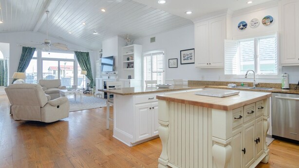 A spacious kitchen with white cabinetry, a large island, and a dining area with a chair and table.