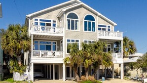 A two-story house with a covered front porch, multiple balconies, and a garage.