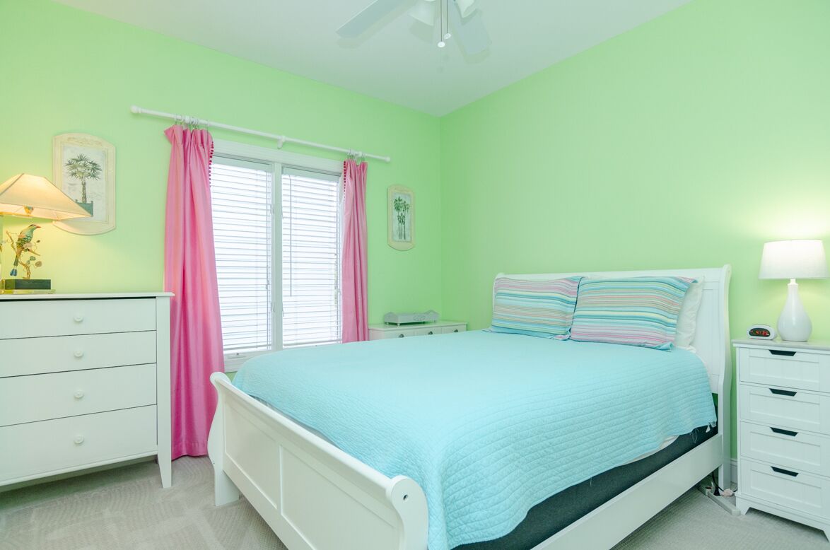 Un dormitorio con cama, mesita de noche, cómoda y ventana con cortinas.