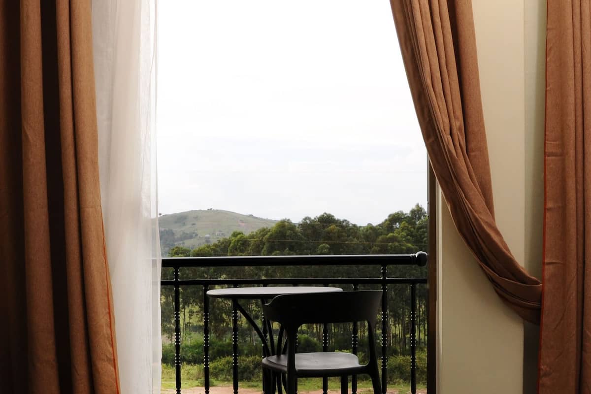 Una habitación con balcón, una silla y un teléfono sobre la mesa.