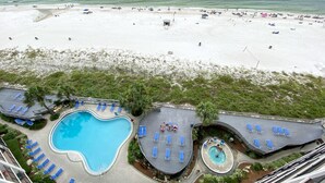 Um resort com uma piscina grande, diversas áreas para banho de sol e uma praia.