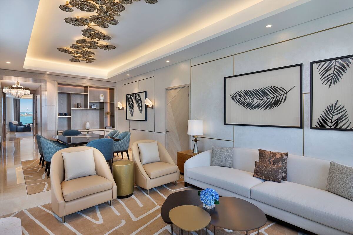 A modern living room with a sofa, armchairs, a coffee table, and a dining area with a table and chairs.