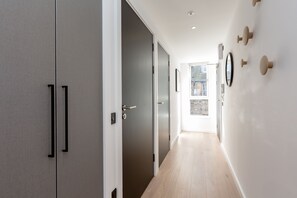 A hallway with a door leading to a balcony, a wall-mounted mirror, and a light fixture. - Destiny Scotland Market St Apartments (Edinburgh)