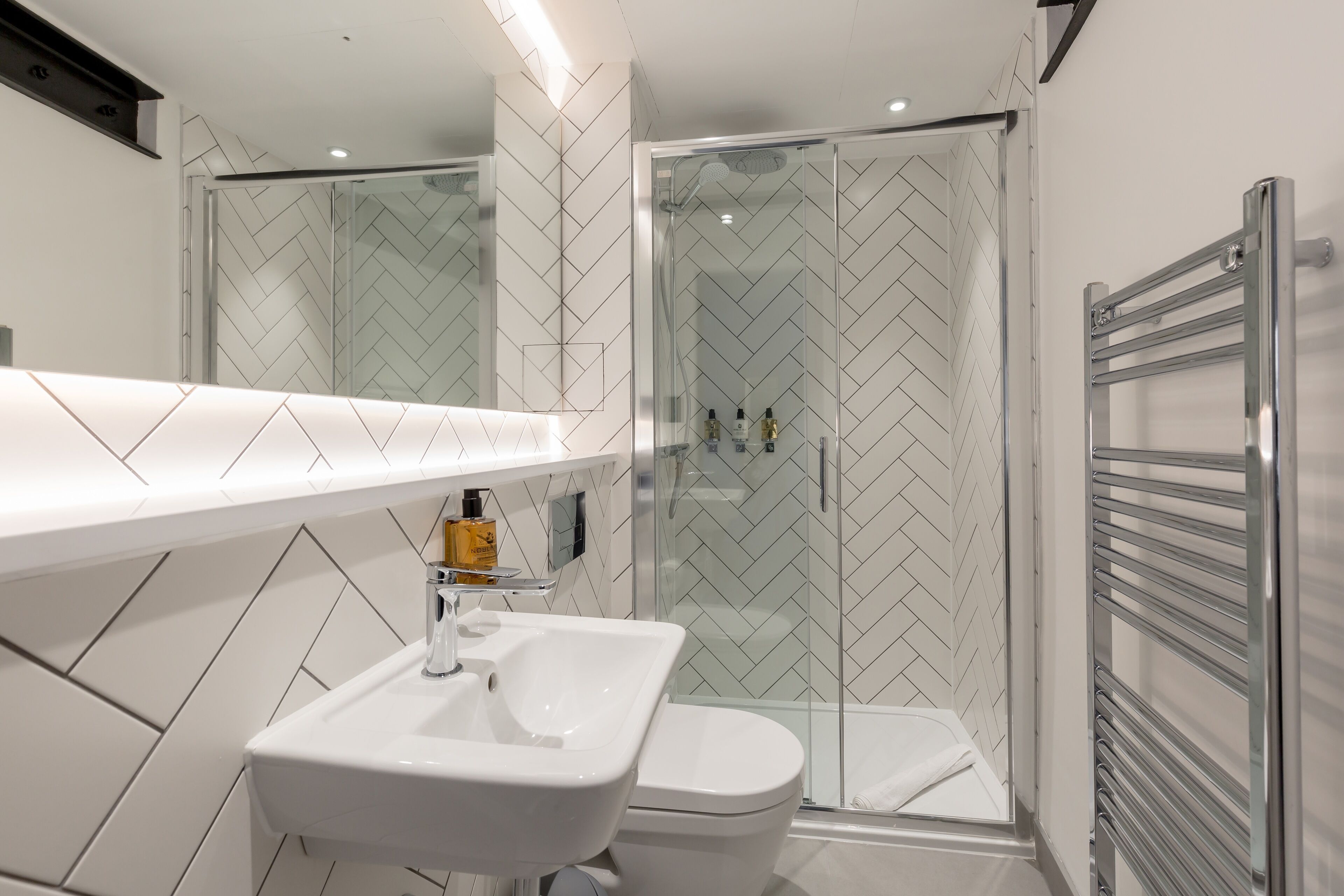 A modern bathroom with a white sink, toilet, and shower area.