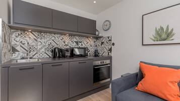 A modern kitchen with grey cabinets, a patterned backsplash, and a built-in oven.