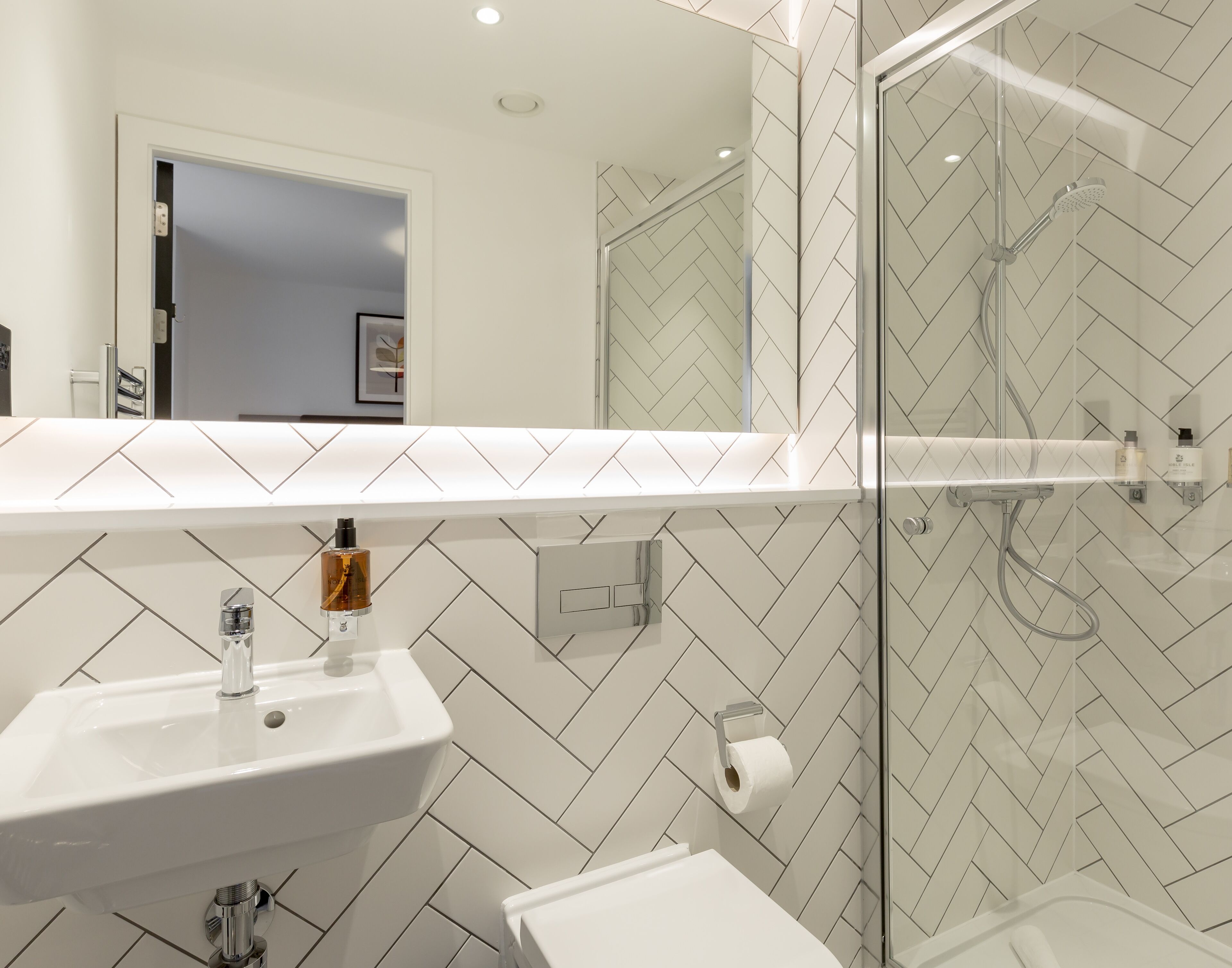 Een moderne badkamer met een wit wastafelmeubel, toilet en douchecabine met glazen wanden.