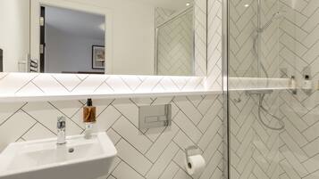 Een moderne badkamer met een wit wastafelmeubel, toilet en douchecabine met glazen wanden.