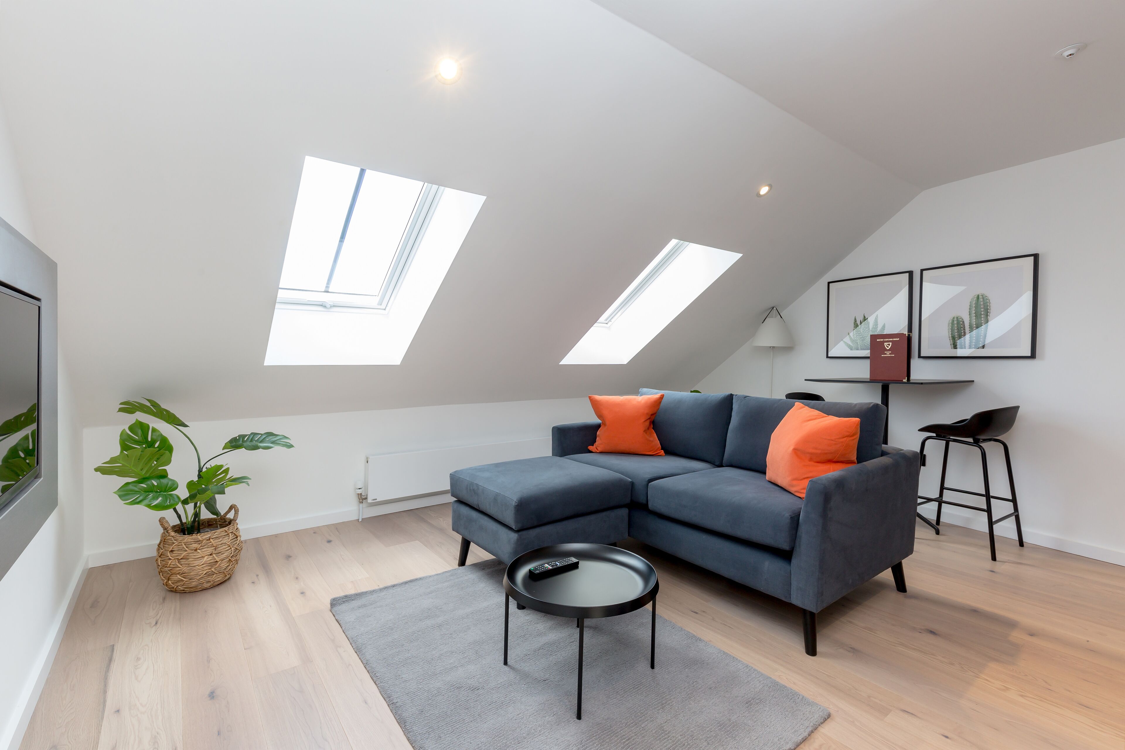 A modern living room with a grey sectional sofa, a small round table, and a potted plant.
