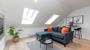 A modern living room with a grey sectional sofa, a small round table, and a potted plant.
