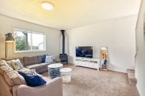 Uma sala de estar com sofá, mesa de centro, televisão e lareira.