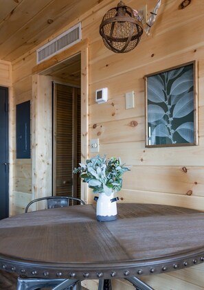 A wooden interior with a round table, chairs, a hanging light fixture, and a framed botanical print on the wall. - Extraordinary Mountain Views/Indoor Pool & Hot Tub (Gatlinburg)