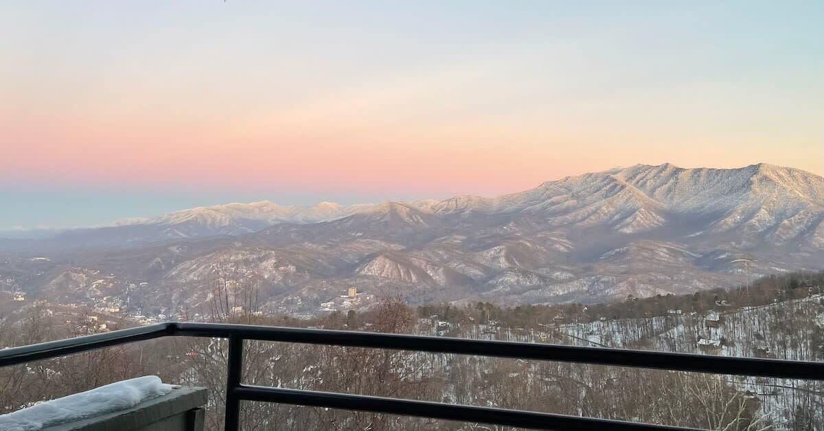 Paisaje montañoso con picos nevados y una ciudad en la parte baja.