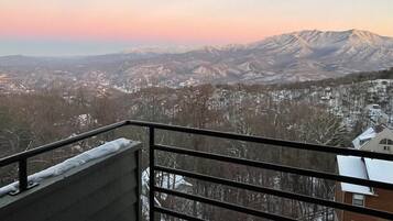 Un balcon offrant une vue sur un paysage montagneux au coucher du soleil.