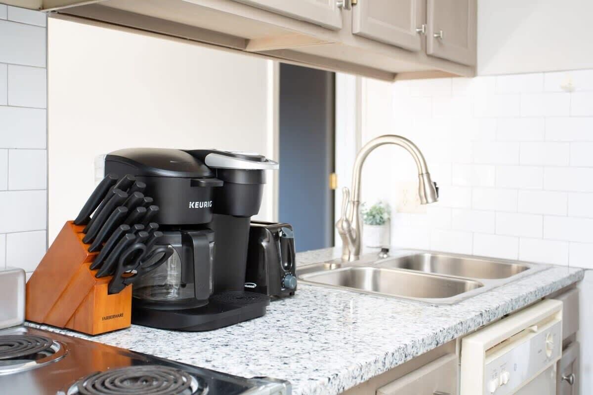 A kitchen with a Keurig coffee maker, a knife block, and a sink.