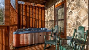 Un bain à remous sur une terrasse en bois, avec des murs en pierre et une clôture en bois.